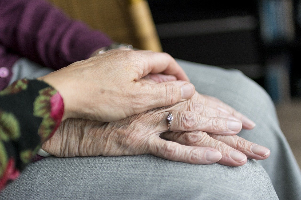 Bild: eine andere Hand beruhigt die Hände einer Seniorin