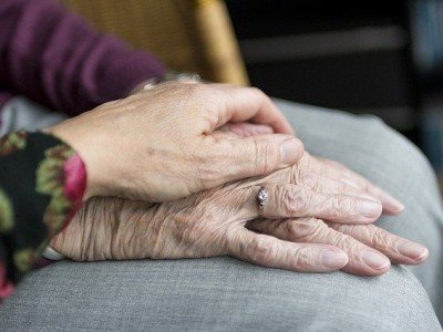 Bild: eine andere Hand beruhigt die Hände einer Seniorin