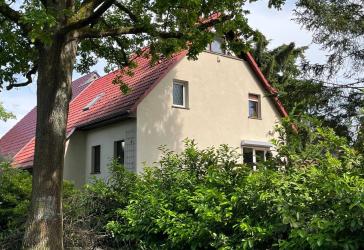 Architektonisch reizvolle Haushälfte mit Einliegerwohnung und zwei Garagen in ruhiger Grünlage